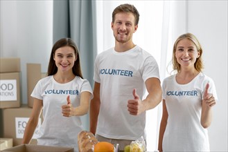 Smiley volunteers posing while giving thumbs up