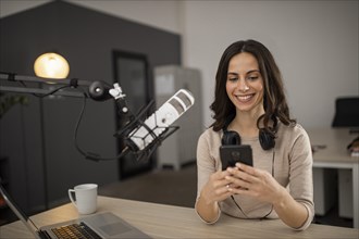 Smiley woman doing podcast radio with microphone smartphone