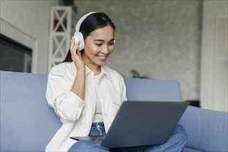 Smiley woman with headphones working laptop
