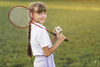 Smiling girl holding badminton her shoulder shuttlecock