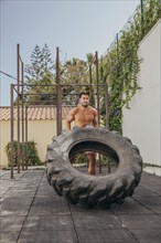 Sporty man lifting wheel