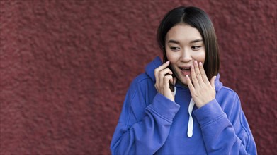 Surprised asian woman talking phone