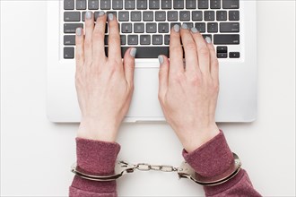 Top view hands with handcuffs working laptop