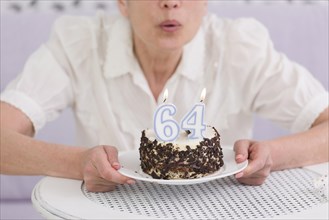 Woman blowing number candles her birthday cake table