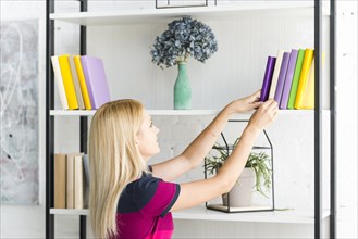 Woman choosing book from shelf home