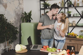 Young couple holding champagne flute standing kitchen counter