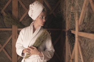 Young woman bathrobe holding medical herbs