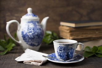 Antique porcelain tea cup teapot with books folded napkin wooden table