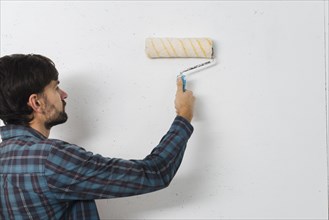 Close up man painting wall with paint roller