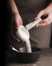 Cook adding sugar from mortar into bowl