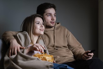 Couple couch watching tv eating chips
