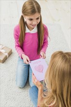 Cute daughter giving greeting card mother