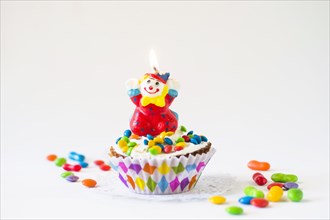 Decorative cup cake with illuminated clown candle white background