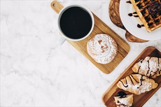 Elevated view coffee cup baked buns croissant waffles wooden tray against marble textured background