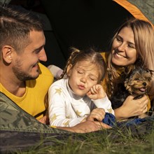 Family sitting tent with their dog close up