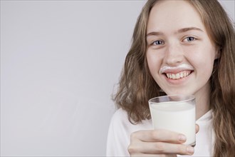 Front view blonde girl holding glass milk