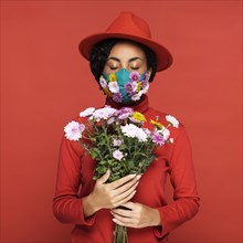 Front view woman with mask holding flowers