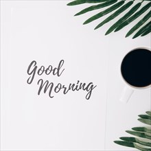 Good morning text paper with coffee cup leaves against white background