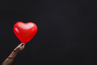 Hand holding heart shaped balloon