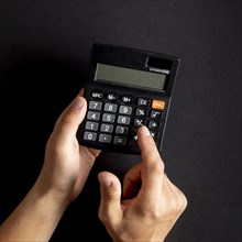 Hands using black mini calculator