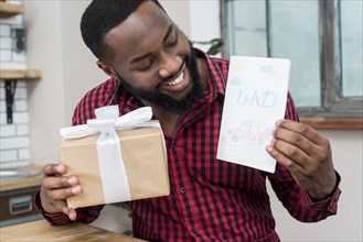 Happy black man holding greeting card gift