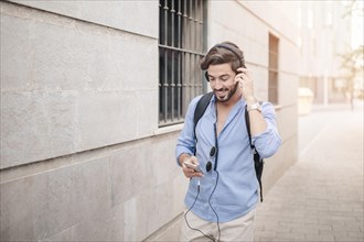 Happy man walking pavement listening music