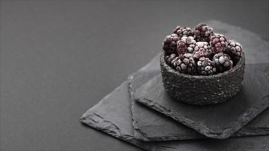 High angle frozen blackberries bowl with slate