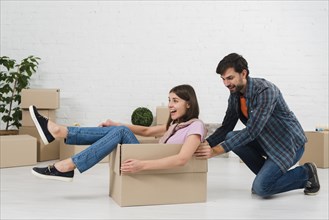 Husband pushing his wife sitting cardboard box