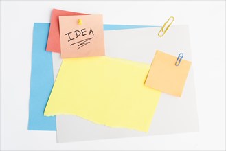 Idea text written sticky note with pushpin paperclip white board