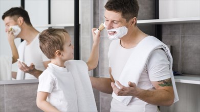 Little boy applying shaving foam his father s face with brush bathroom