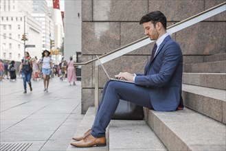 Man suit using laptop street