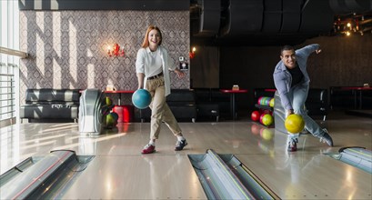 Man woman throwing bowling balls alley