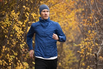 Mid shot man running trail forest