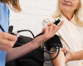 Nurse checking old woman s blood pressure