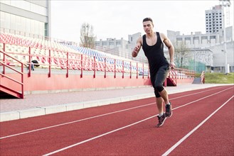 Portrait fitness young male athlete running race track stadium
