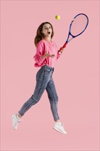 Portrait happy woman jumping with tennis racket