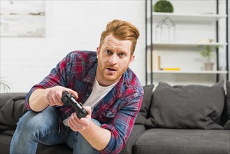 Portrait serious man playing video game with joystick home