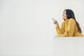 Pretty woman pointing something standing balcony