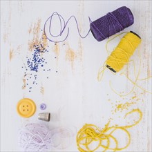 Purple yellow yarn ball button with beads white wooden textured backdrop