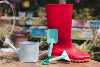 Red rubber boot blue shovel watering can table garden