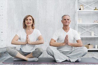 Senior family couple sitting lotus pose grey yoga mat