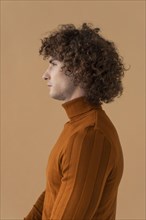 Side view curly haired man with brown blouse posing