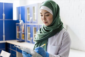 Side view female scientist with hijab notepad