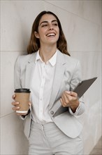 Smiley elegant businesswoman holding tablet coffee cup