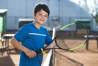 Smiley kid resting tennis net