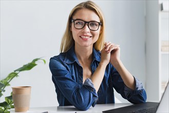 Smiling blonde employee with glasses looking camera