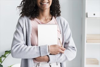 Smiling young woman holding notebook workplace