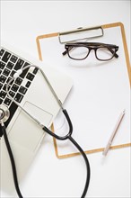 Stethoscope laptop clipboard with eyeglasses pen white background