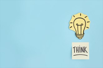 Think sticky note hand drawn yellow light bulb blue background