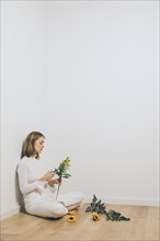 Thoughtful woman sitting with plant branches